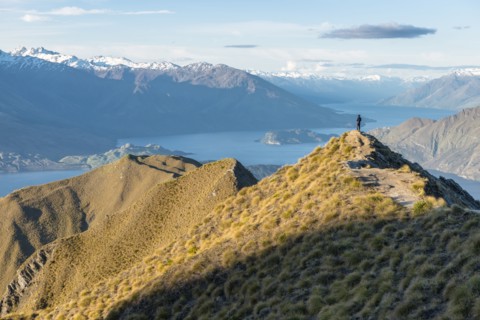 Man standing on mountain peak by Lake Wanaka, New Zealand