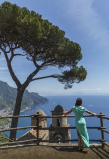Woman leaning on fence by church in Ravello, Italy