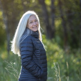 Mature woman wearing black jacket by forest
