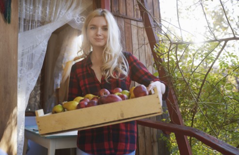 Young woman holding crate of apples