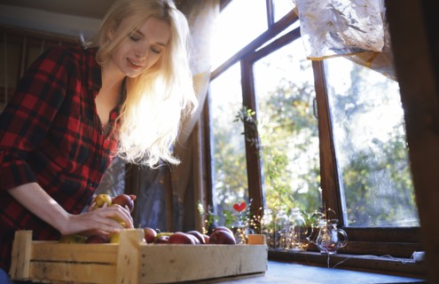 Woman with crate of apples by window