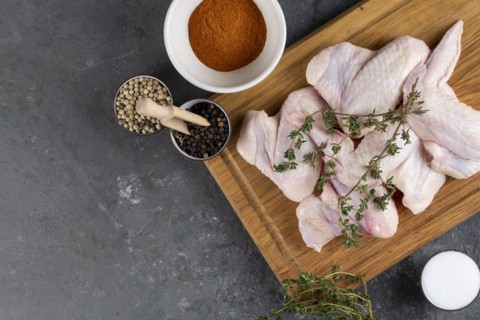 Raw chicken on cutting board with herb and spices