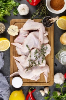 Raw chicken on cutting board surrounded by ingredients