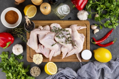 Raw chicken on cutting board surrounded by ingredients