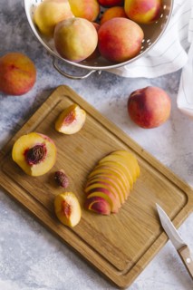 Peaches sliced on wooden cutting board