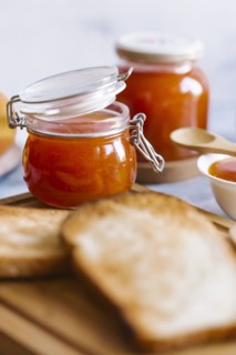 Jars of apricot jam by toast