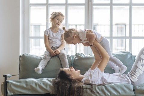 Mother playing with her daughters on sofa