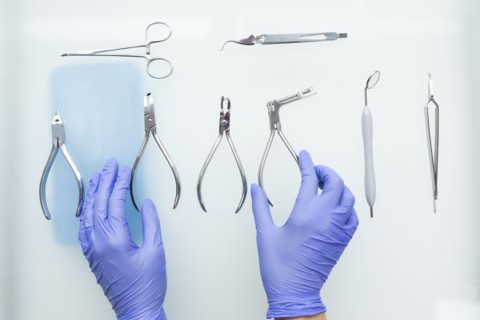 Hands of dental assistant wearing rubber gloves with dental equipment