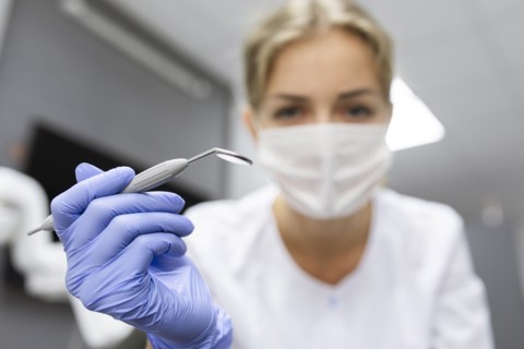 Patient point of view of dental assistant holding dental equipment