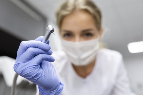 Patient point of view of dental assistant holding dental equipment