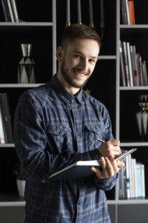 Smiling young businessman writing in note pad