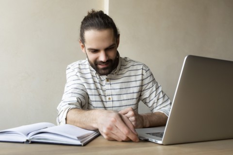 Young businessman putting USB stick into laptop