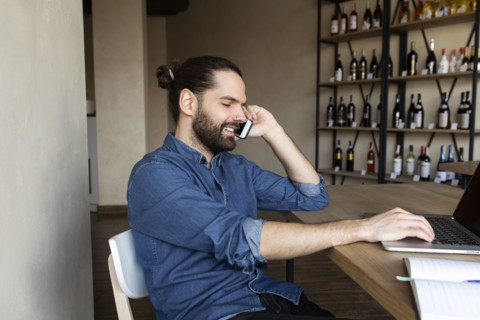 Young businessman on phone by laptop