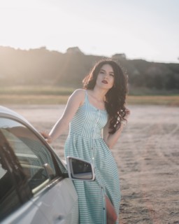 Young woman wearing striped dress by car