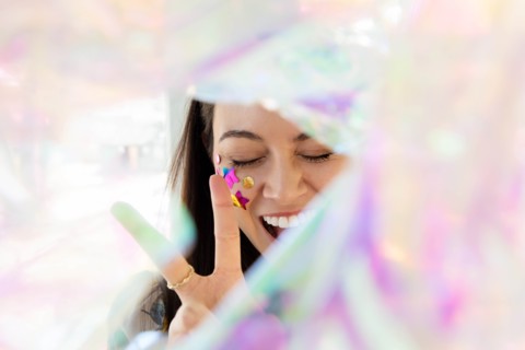 Woman with confetti on cheek making peace gesture