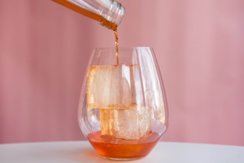 Liquor being poured into glass with ice cubes