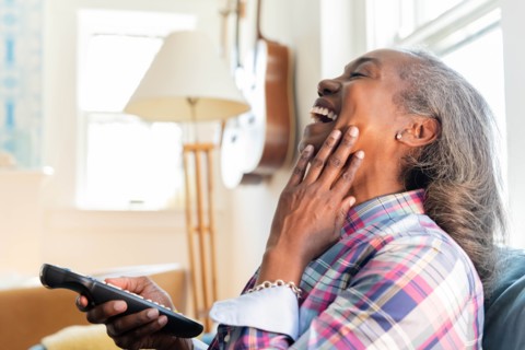 Mature woman with remote control watching television