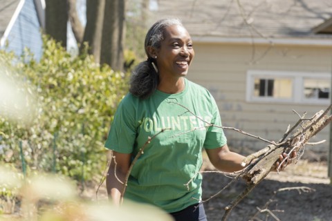 Mature woman volunteer collecting branches in garden