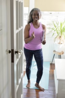 Smiling mature woman with clipboard on yoga mat