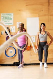 Women exercising with battle ropes in gym