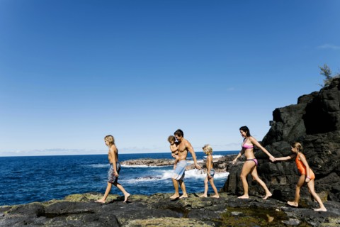 Family walking on rocks by sea