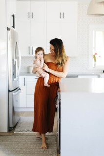 Woman carrying her baby daughter in kitchen