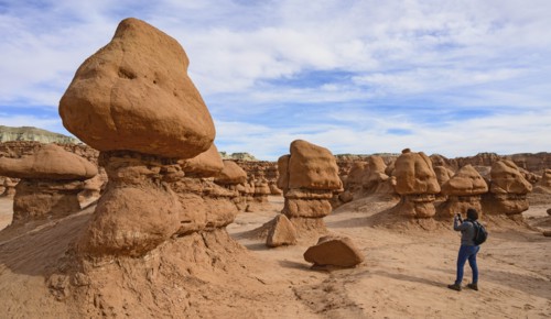 Woman photographing hoodoos in Goblin Valley State Park, Utah, USA