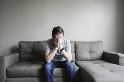 Depressed mature man sitting on couch