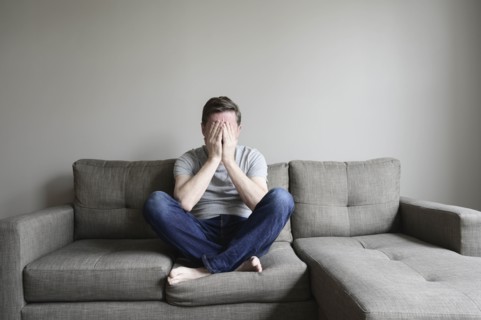 Depressed mature man sitting on couch