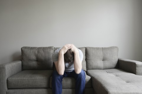 Depressed mature man sitting on couch