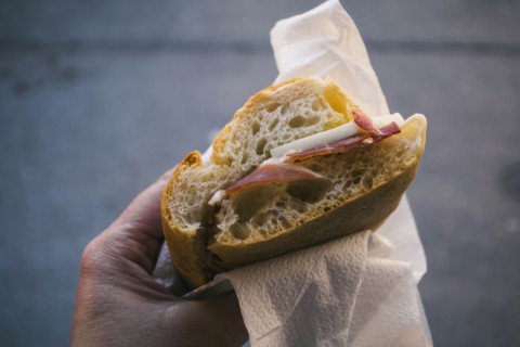 Woman's hand holding pancetta and cheese sandwich