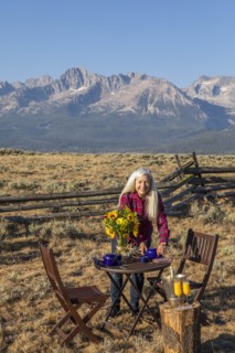Mature woman setting dining table in field by mountain in Stanley, Idaho