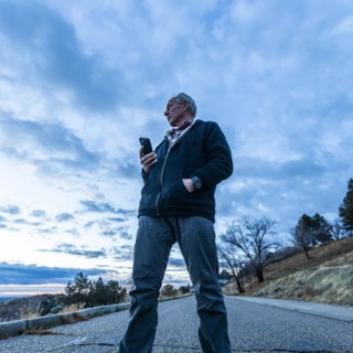Low angle view of man holding smart phone on road