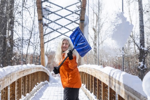 Mature woman shoveling snow off of footbridge