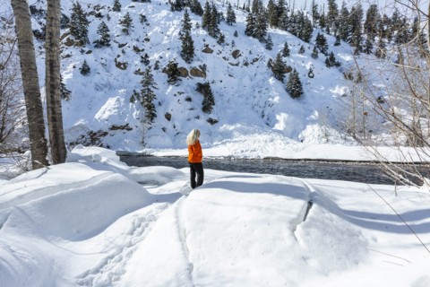 Mature woman wearing orange coat on snow by river