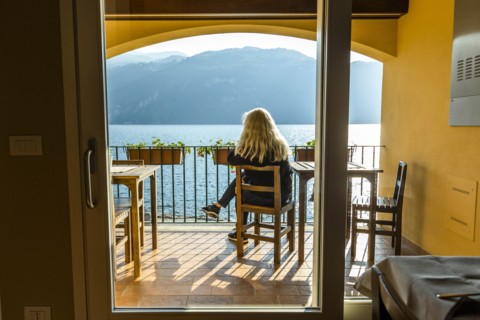 Mature woman sitting on balcony by Lake Como in Lombardy, Italy