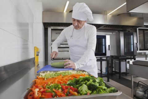 Chef slicing squash in commercial kitchen