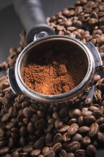 Portafilter holding ground coffee on roasted coffee beans