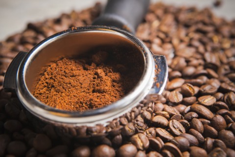 Portafilter holding ground coffee on roasted coffee beans