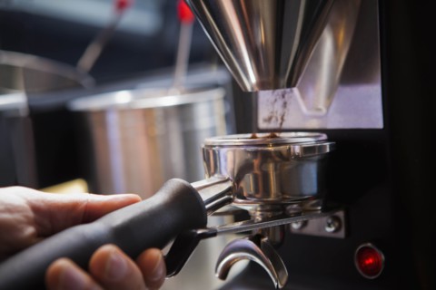 Barista collecting ground coffee in portafilter