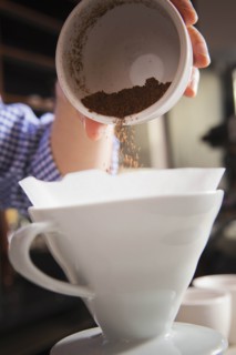 Barista pouring coffee grounds into filter