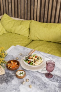 Caesar salad and sauce on table by sofa