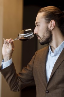 Young man smelling wine in glass at tasting
