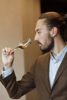 Young man smelling wine in glass at tasting