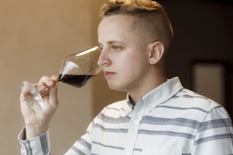 Young man smelling wine in glass at tasting