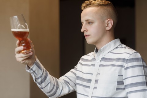 Young man examining glass of beer