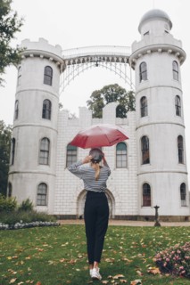 Woman holding red umbrella by Schloss Pfaueninsel in Potsdam, Germany