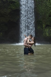 Young couple embracing in river by Tibumana Waterfall in Bali, Indonesia