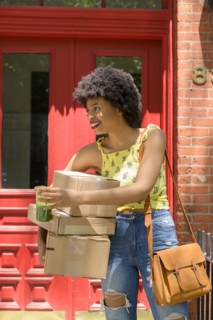 Woman carrying cardboard boxes and green juice