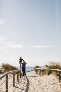Father helping his son walking on fence on beach